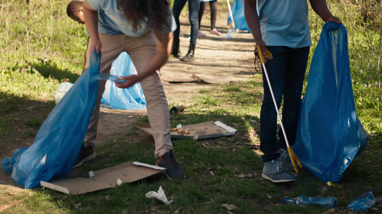Diverse men volunteers pick up rubbish and plastic trash with tongs