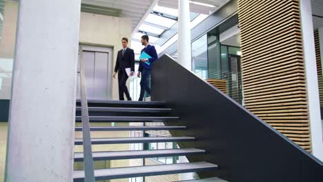 Businessmen-interacting-with-each-other-while-walking-on-stairs
