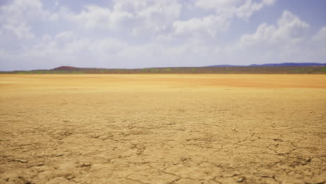 dry landscape with cracked earth under a blue sky in midday sunshine