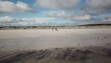 vista aérea de tres personas en una playa de arena en connemara, irlanda, revelando el océano