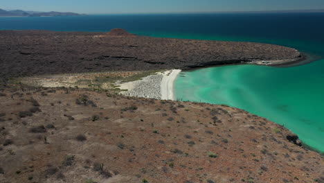 Cinematic-drone-shot-of-Balandra-Beach,-passing-over-the-red-hills,-turquoise-waters-and-white-sand-beaches