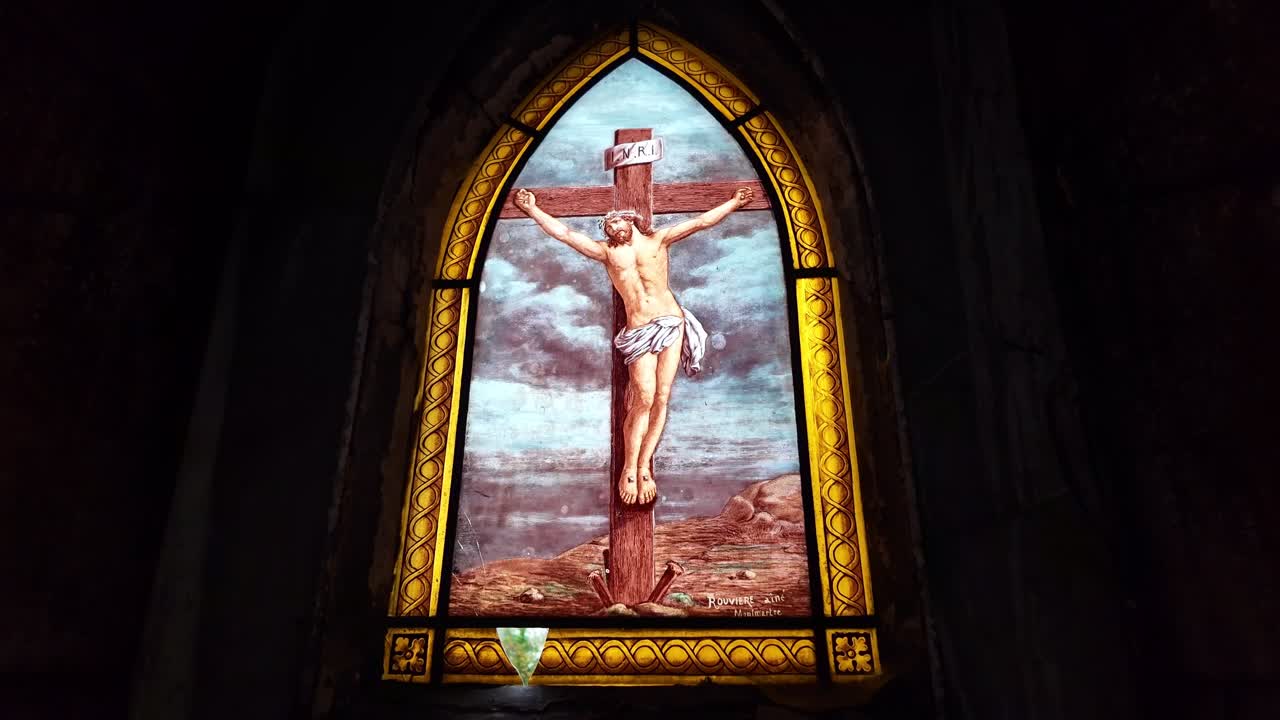 Gambar close-up bergerak ke arah kaca patri yang menggambarkan Yesus Kristus di kayu salib