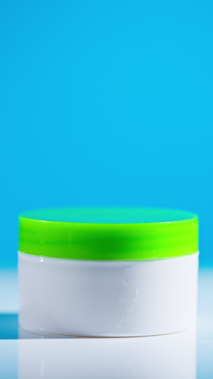 White cosmetic jar with green lid