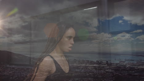 composite of biracial woman with dreadlocks running, and coastal landscape with cloudy blue sky