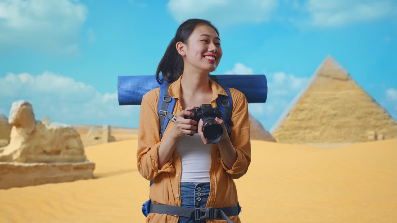 Asian Female Hiker With Mountaineering Backpack Smiling And Holding A Camera In Her Hands Then Looking Around While Traveling In Pyramid Of Giza