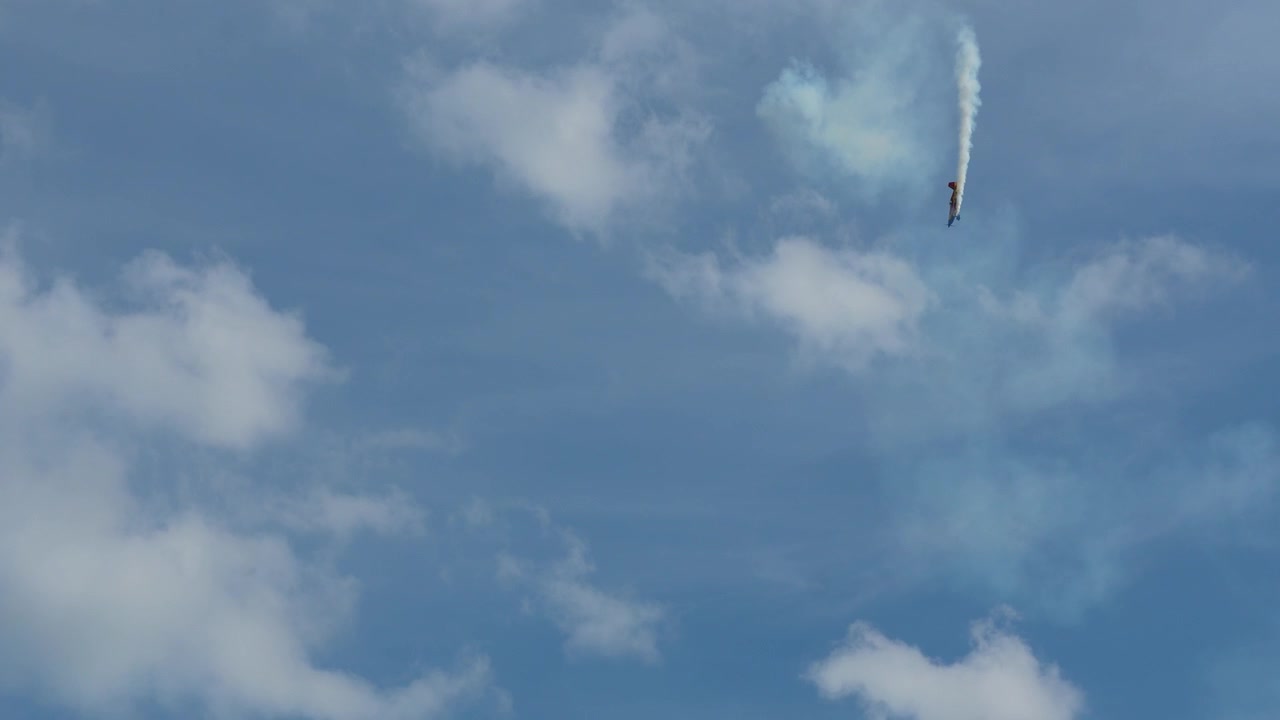 Aereo acrobatico che esegue una drammatica manovra di picchiata verticale durante uno spettacolo aereo a Iasi, Romania, contro un cielo blu nuvoloso.