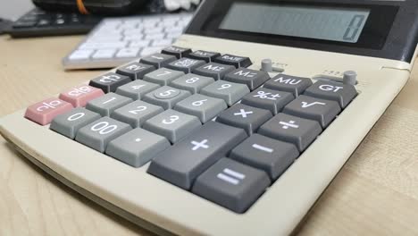 A well-worn, large calculator sits close-up on a desk. Its faded appearance shows frequent use, a testament to countless computations.