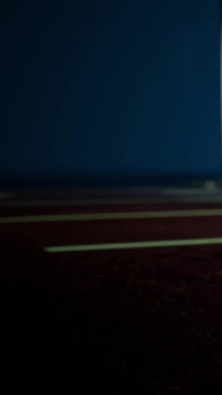Running on a track during evening practice with focused preparation ahead