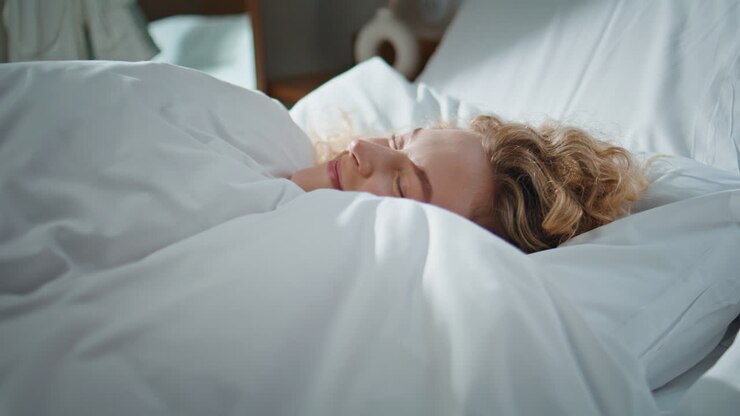 Morning woman resting bedroom in sunlight. Closeup curly girl peeking blanket