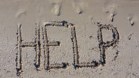 static shot of help written in the sand and filling the frame