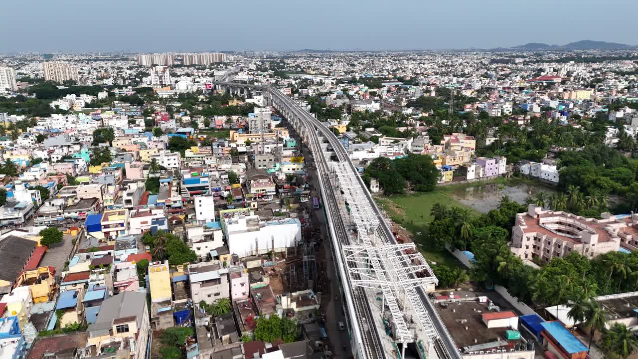 Vista aerea di un ampio paesaggio urbano dell'India meridionale con una grande linea della metropolitana sopraelevata e sinuosa che attraversa quartieri residenziali e commerciali densi e colorati