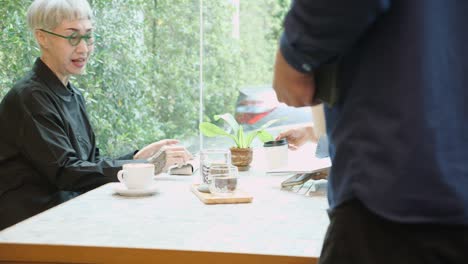 senior woman talking about agreement of project and explaining with businesspeople in the cafe, elderly conversation and deal with partnership about business in the coffee shop, adviser and agent.