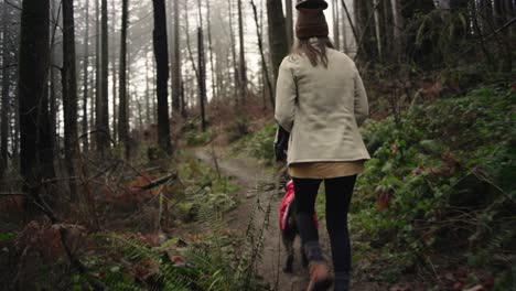 female hiker with labradoodle dog in raincoat