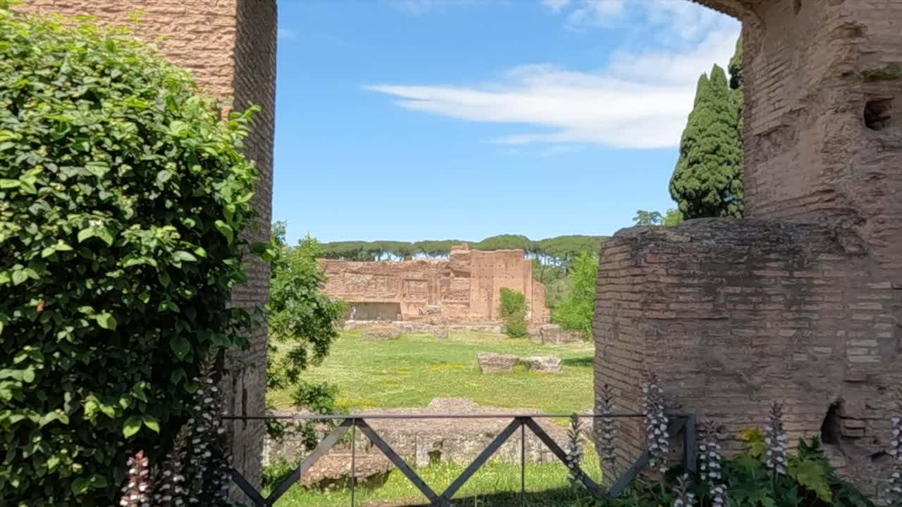 Vista panoramica di antiche rovine archeologiche romane incorniciate da un arco storico in mattoni. Architettura storica con verde sotto il cielo blu in un famoso sito del patrimonio italiano a Roma