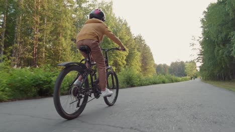 rear view of kid riding a bike in forest path while other people are running