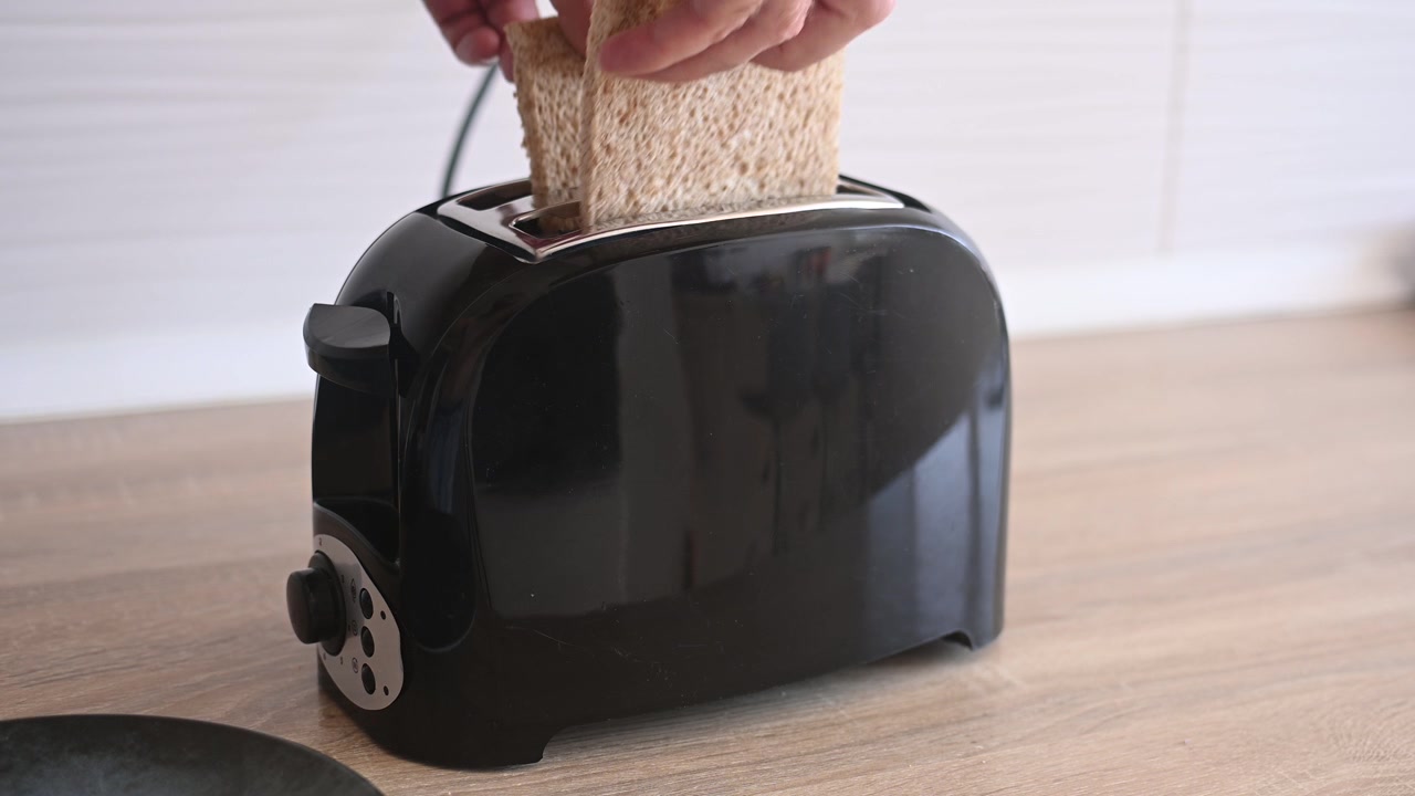 Placing bread slices into a toaster to make breakfast toast