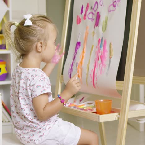 little girl painting with her hand