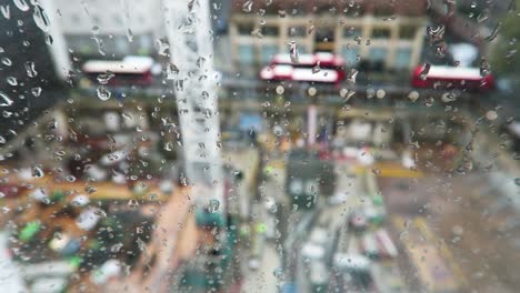 Nahaufnahme-Von-Regentropfen-Auf-Einem-Fenster-Mit-Blick-Auf-Baustelle-Und-Rote-Londoner-Busse-Im-Hintergrund