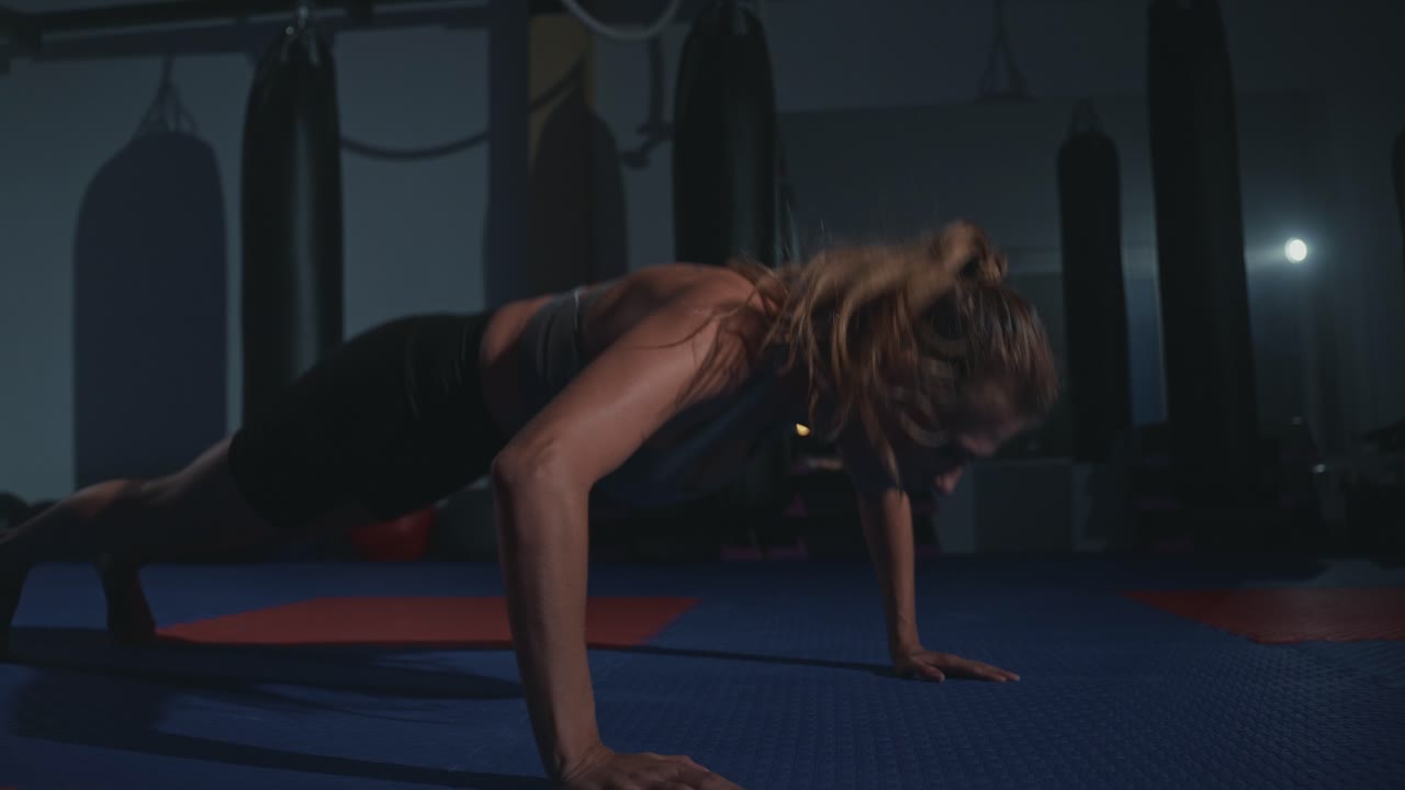 Determined Woman Doing Push-ups in a Dark Gym