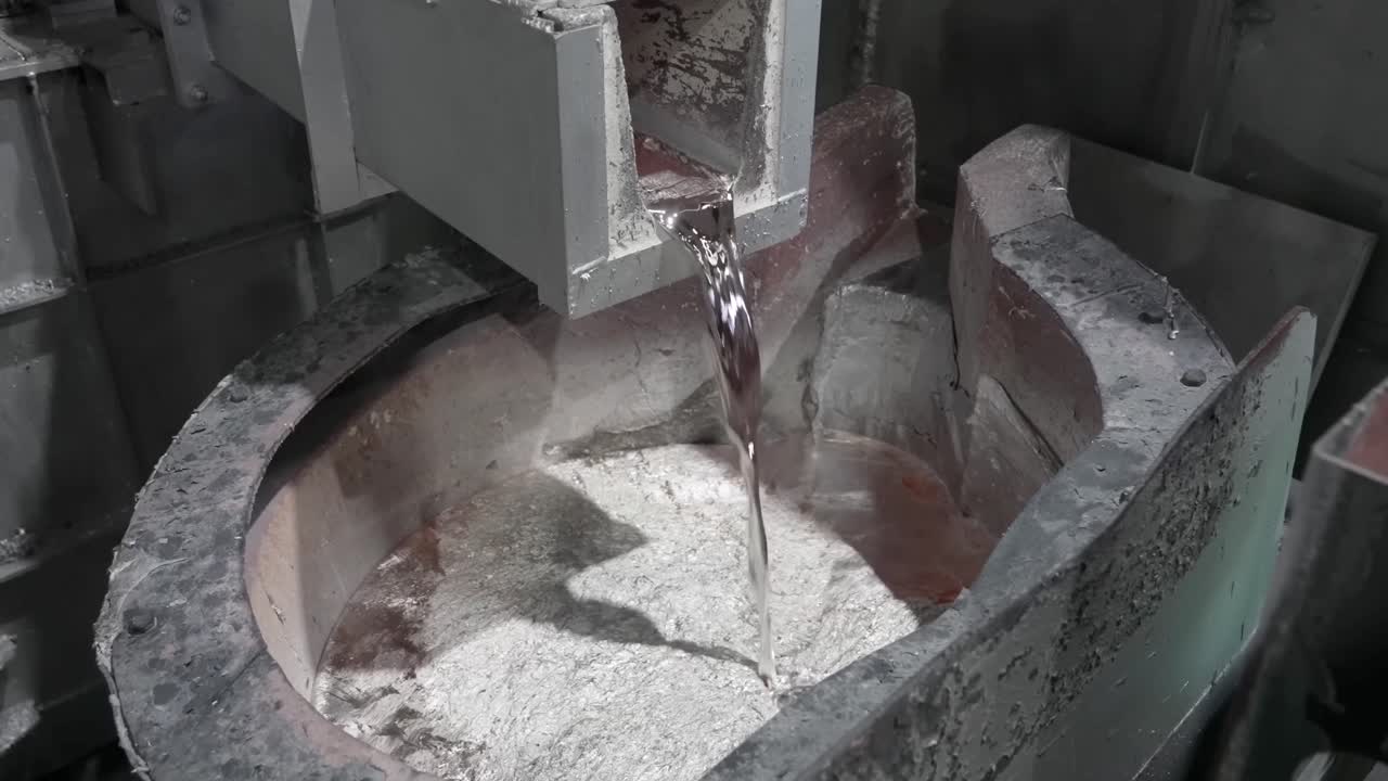 Strøm af smeltet aluminium, der hældes fra en ovn ned i en digel på et højtemperatur-metalstøberi.