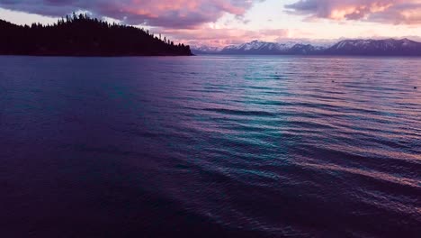 Rising-perspective-aerial-reveal-over-Lake-Tahoe-at-sunset-with-winter-Sierra-Nevada-mountains-background