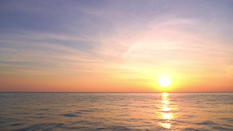 A-giant-yellow-sun-hangs-on-the-horizon-as-it-begins-to-set-into-the-ocean-waters