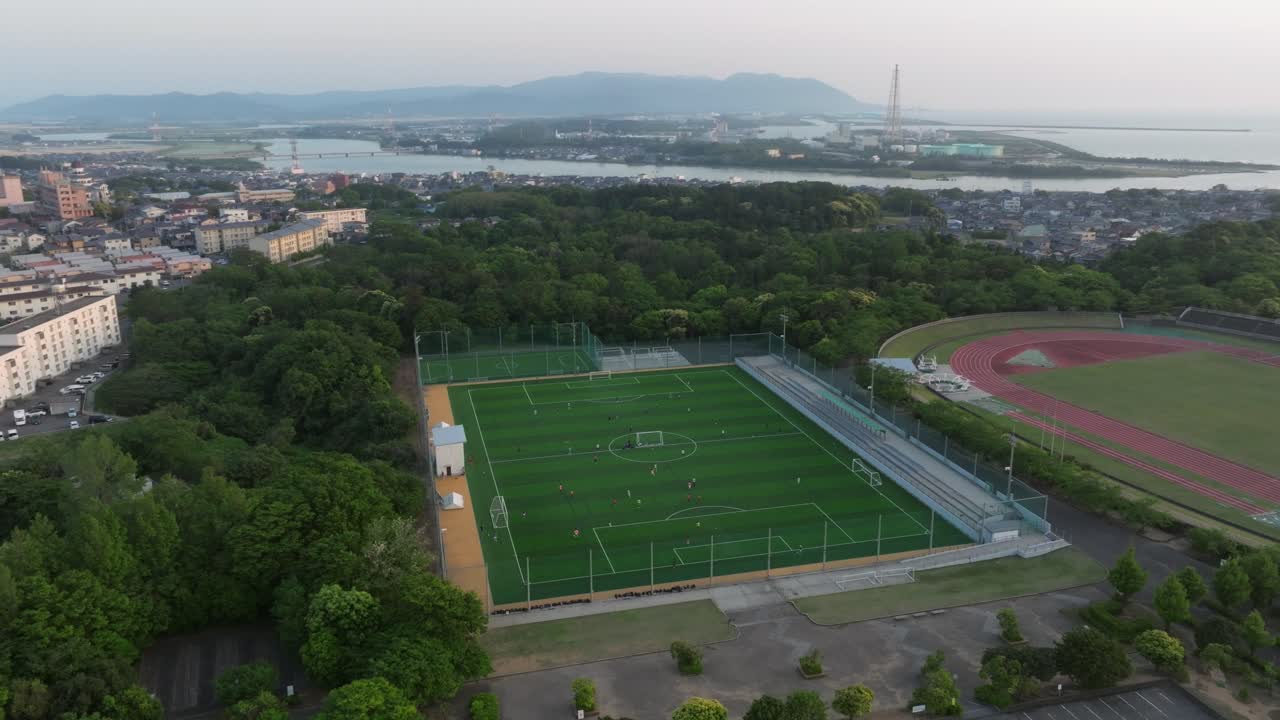 vuelo aéreo de drones campus panorámico, campo de fútbol con jugadores en un partido de fútbol, escuela en la ciudad de fukui, japón