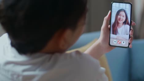 close up of a man having video call with a woman on smartphone in the living room