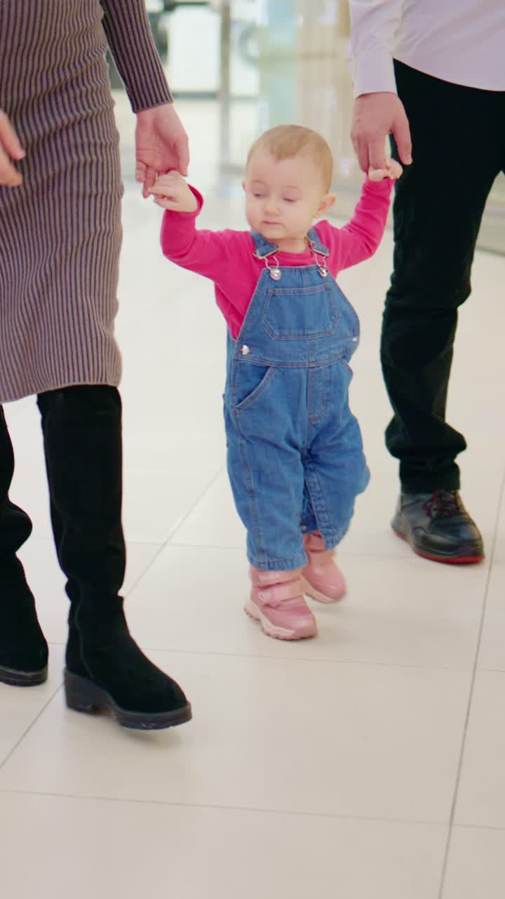 Ein fröhliches Kleinkind genießt einen Tag im Freien, Hand in Hand mit einem Elternteil, trägt ein verspieltes Outfit und erkundet vergnügt die moderne Umgebung