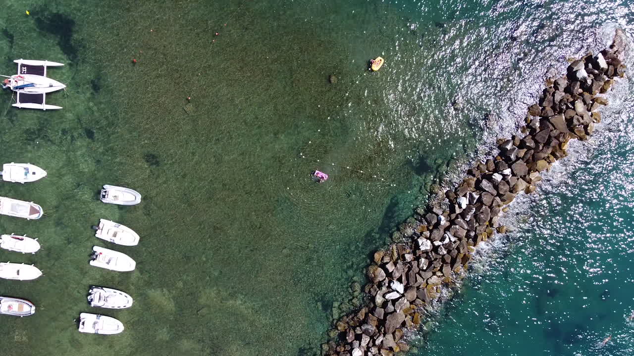 바다에서 스피드 보트와 요트를 볼 수 있는 새의 눈 공중 전망과 햇빛 반사가 있는 작은 바위 해안