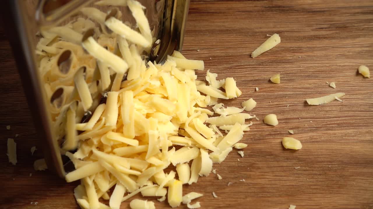 Il cuoco grattugia il formaggio su una grattugia. Rallentatore