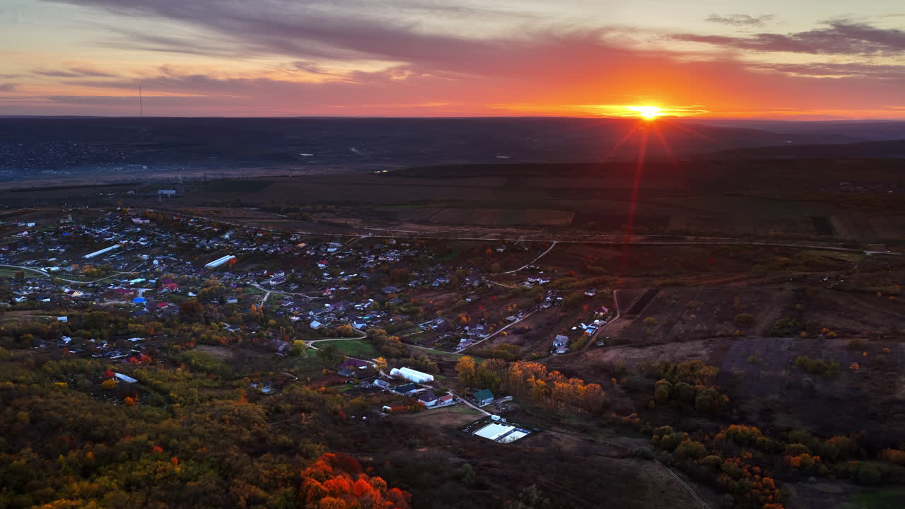 Aerial drone view of the sun setting over a Moldovan village surrounded by farmlands