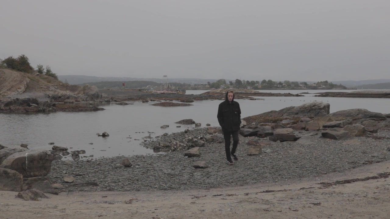 Uomo che cammina verso la fotocamera sulla costa rocciosa della penisola di Bygdøy a Oslo