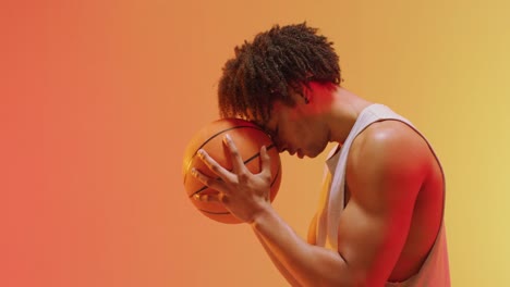 video of biracial male basketball player with ball on orange to yellow background