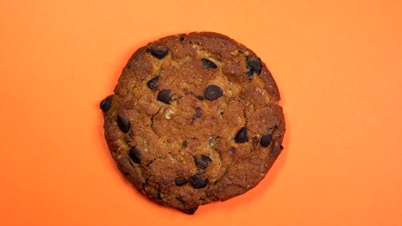 una galleta de chocolate en primer plano, una foto macro, girando lentamente sobre un fondo naranja giratorio.
