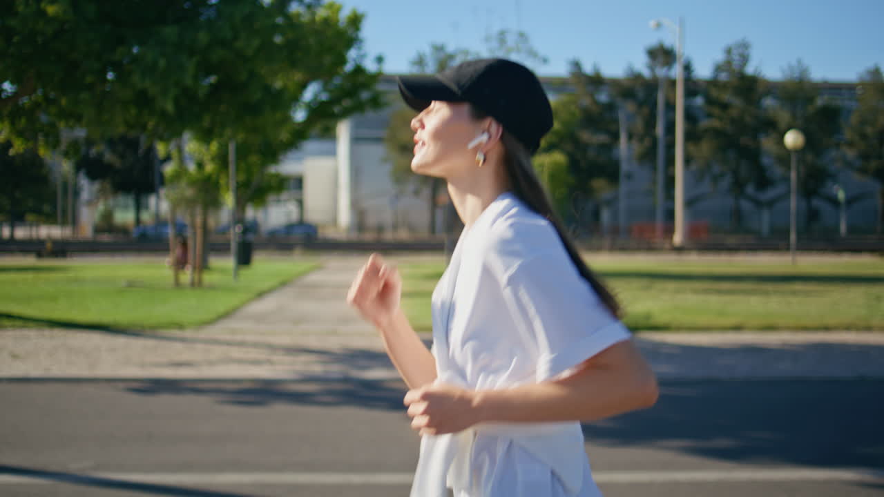Happy girl jogging road wearing wireless earbuds closeup. Smiling woman running
