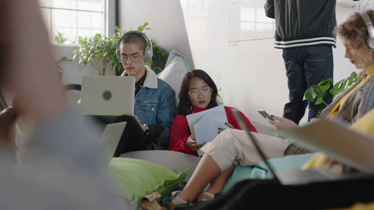 grupo de jóvenes empresarios estudiantes que trabajan juntos compartiendo información intercambiando ideas estudiando usando tecnología de computadoras portátiles discutiendo proyectos socializando en un lugar de trabajo de oficina relajado