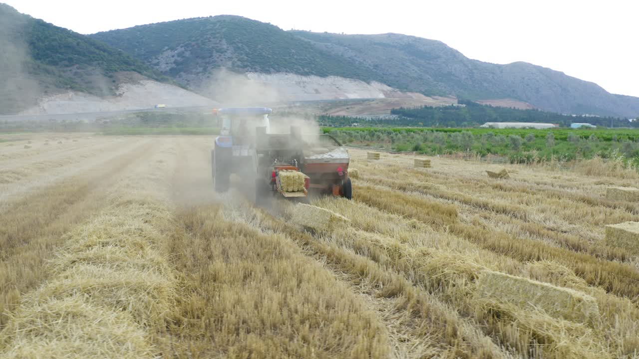 풀로 가득 찬 트레일러를 고 있는 트랙터를 타고 있는 농부.