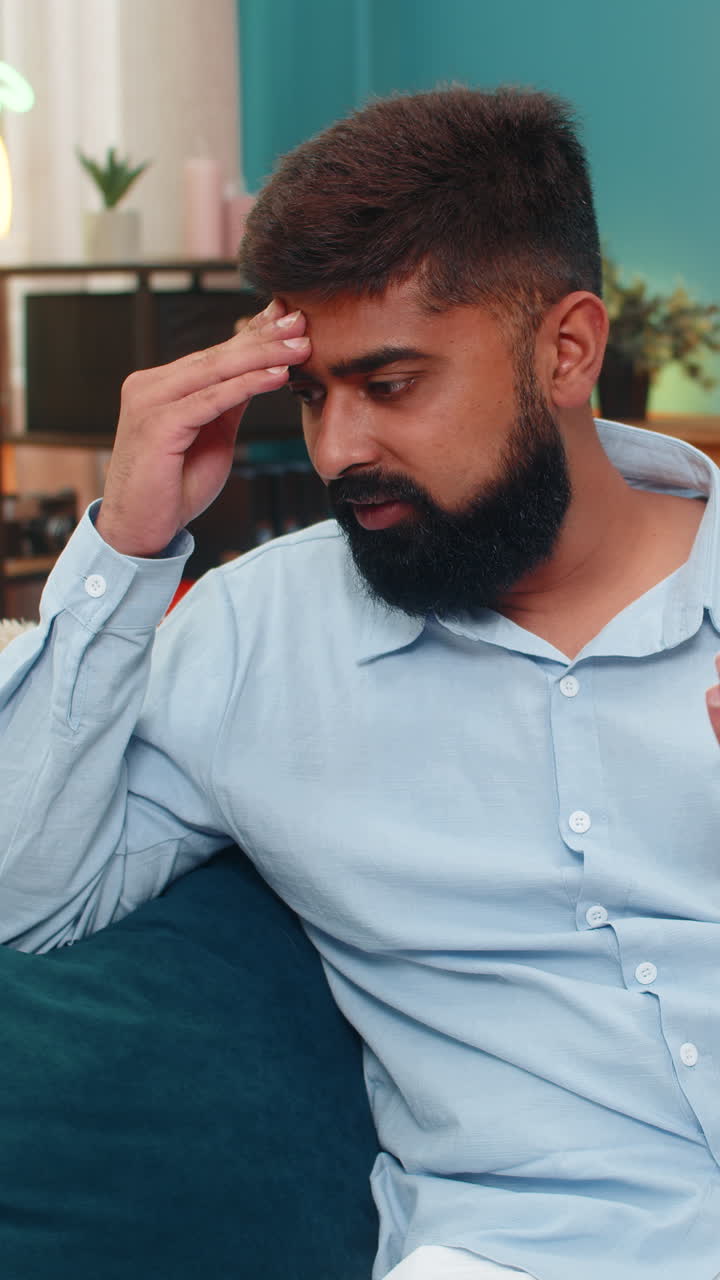 Indian man facepalm slaps forehead disappointed smartphone mistake shows frustration regret indoors