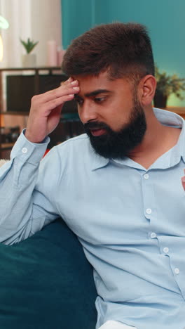 indian man facepalm slaps forehead disappointed smartphone mistake shows frustration regret indoors