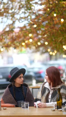 two women friends relaxing at an outdoor cafe in autumn