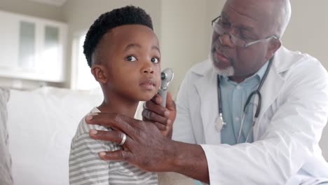 Médico-Afroamericano-Senior-Revisando-El-Oído-De-Un-Paciente-Niño-Con-Otoscopio,-Cámara-Lenta