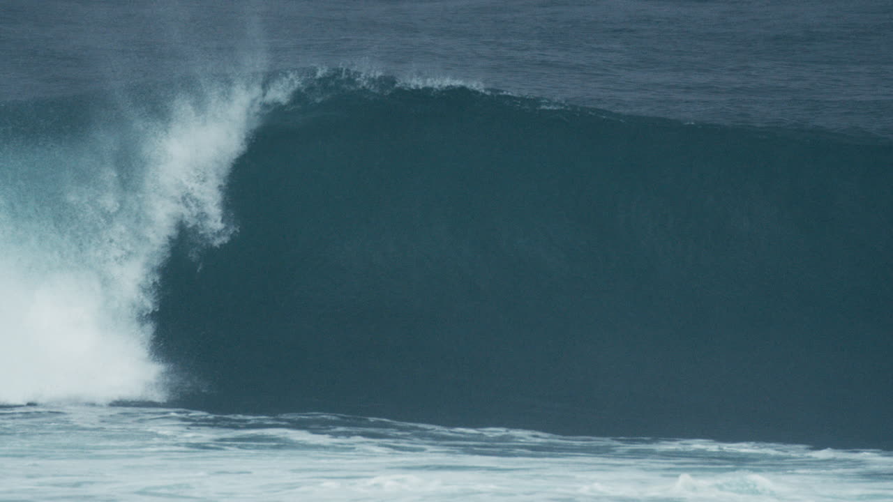 Curling barrel wave crashes with dramatic motion and deep blue tones
