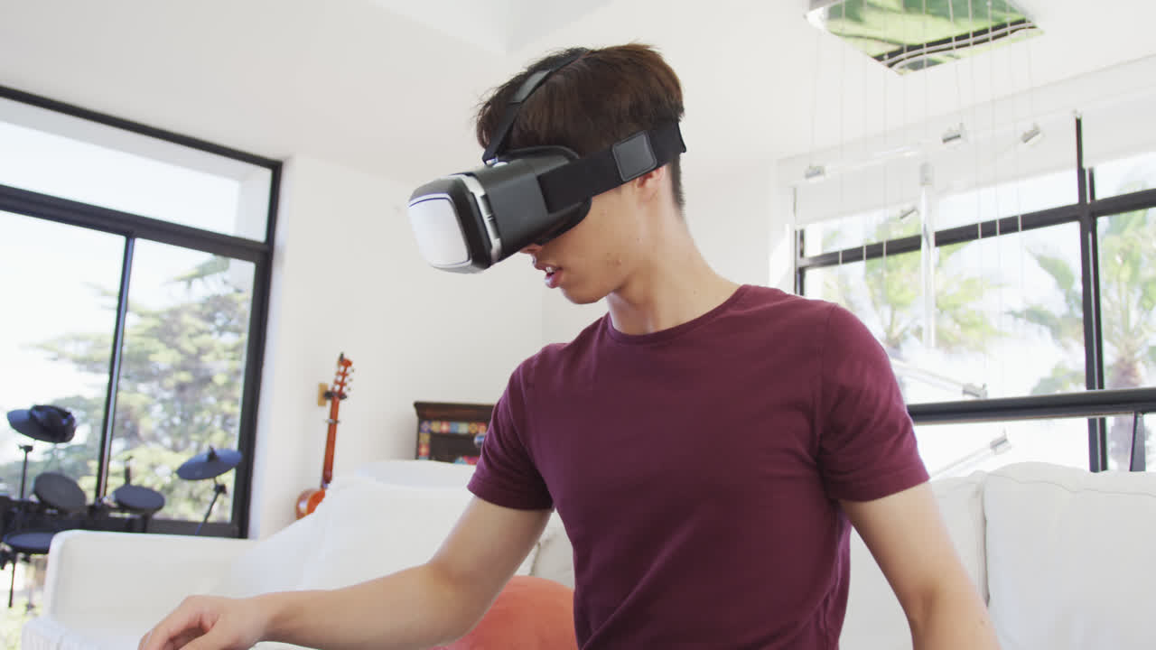 Asian boy wearing vr headset gesturing in living room at home