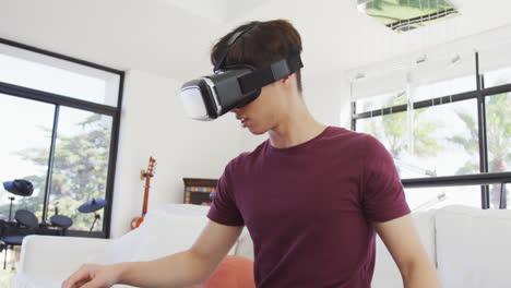 Asian-boy-wearing-vr-headset-gesturing-in-living-room-at-home