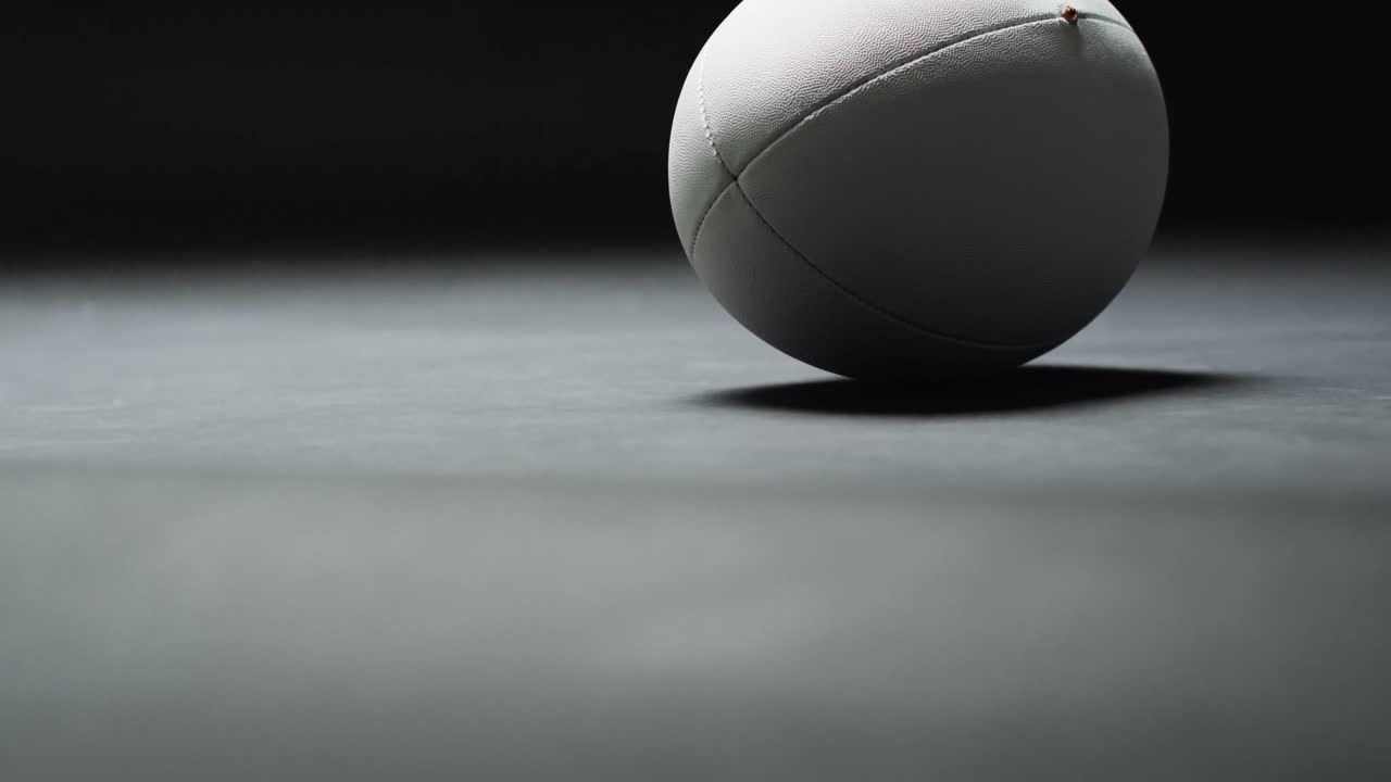 Ballon de rugby blanc sur fond sombre avec un espace pour le texte, au ralenti.