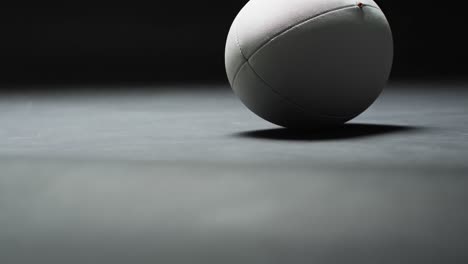 White-rugby-ball-on-dark-background-with-copy-space,-slow-motion