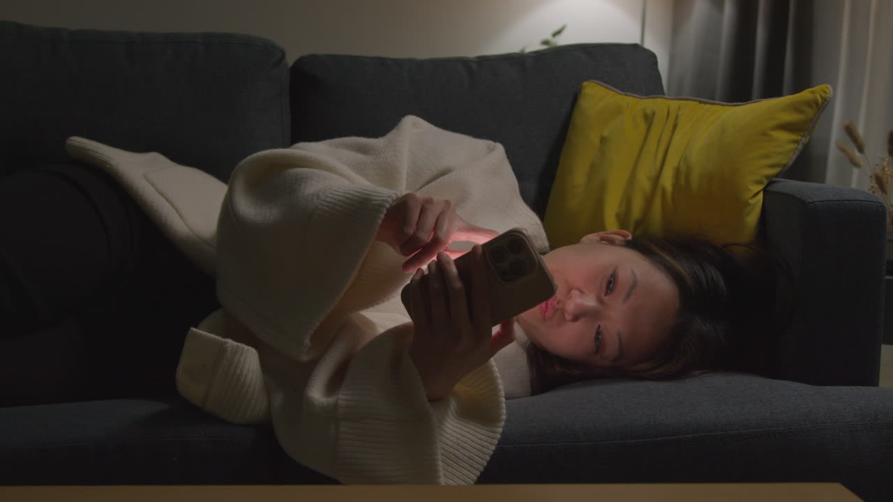 Woman Spending Evening At Home Lying On Sofa With Mobile Phone Scrolling Through Internet Or Social Media 9