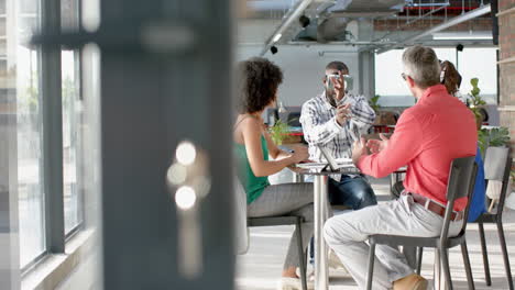 african american businessman wearing vr headset, gesturing while colleagues watching him at office