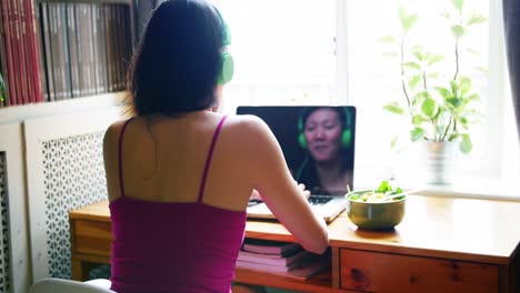 Rear-view-of-woman-listening-songs-while-using-laptop